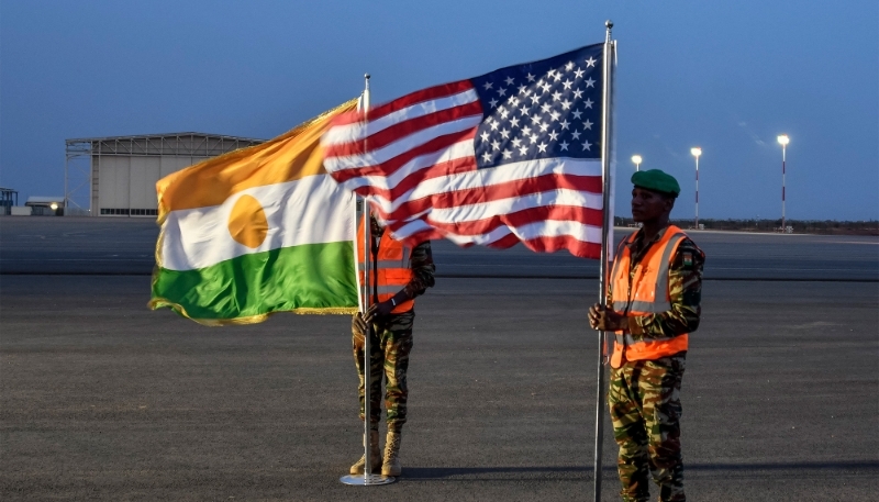 Deux soldats nigériens tiennent les drapeaux américain et nigérien sur la base aérienne 101 à Niamey en juin 2024.