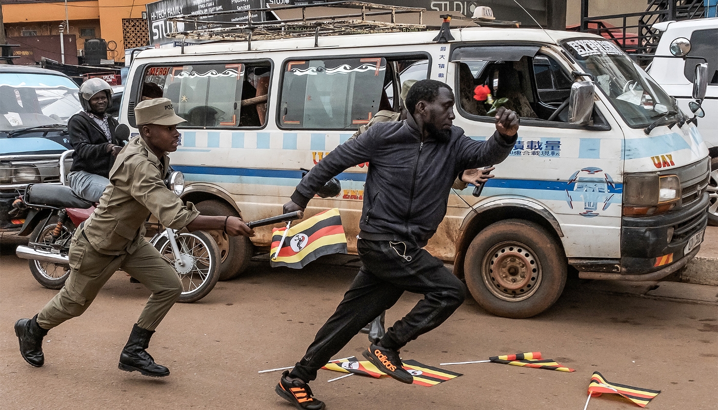 Un policier tente d'arrêter une personne participant à une manifestation en faveur de figures de l'opposition à Kampala, le 2 février 2026.