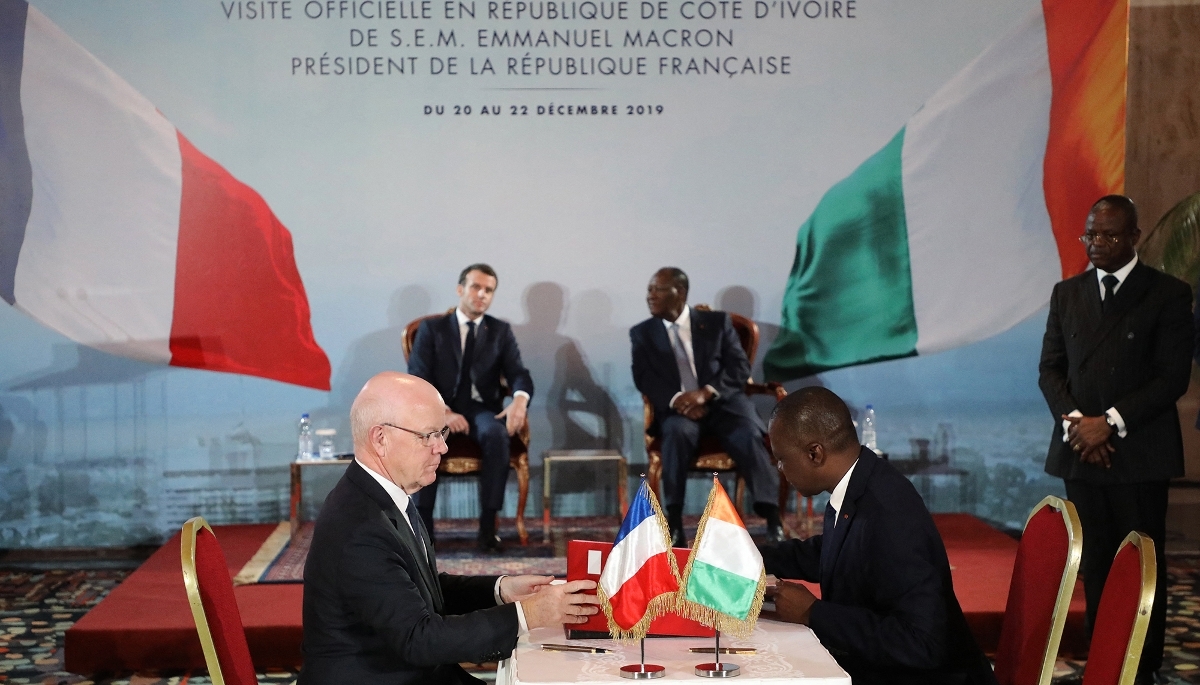 L'ex-PDG de Bouygues Construction Philippe Bonnave (à g.) et le ministre ivoirien des transports, Amadou Koné, signent le contrat du projet de métro d'Abidjan, en présence des présidents français et ivoirien Emmanuel Macron et Alassane Ouattara (en arrière-plan), à Abidjan, le décembre 2019.
