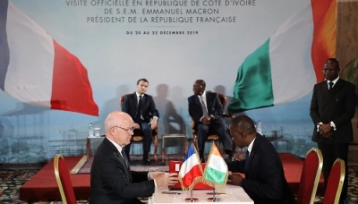 L'ex-PDG de Bouygues Construction Philippe Bonnave (à g.) et le ministre ivoirien des transports, Amadou Koné, signent le contrat du projet de métro d'Abidjan, en présence des présidents français et ivoirien Emmanuel Macron et Alassane Ouattara (en arrière-plan), à Abidjan, le décembre 2019.
