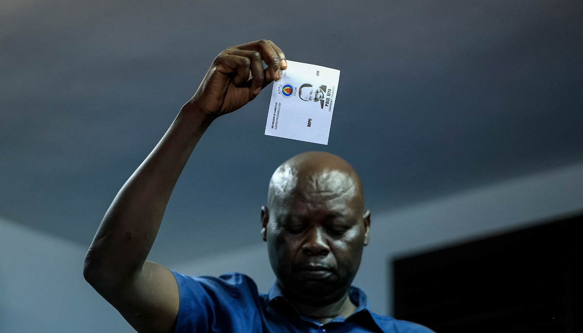 Un membre d'Elecam montre un bulletin de vote à l'effigie de Paul Biya lors du comptage des voix dans un bureau de vote de Yaoundé, le 12 octobre 2025.