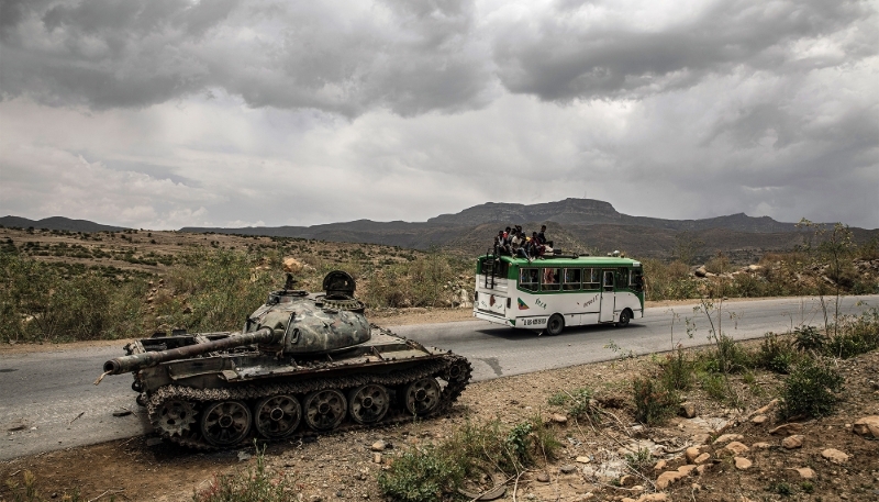 Un bus transportant des civils passe devant un char d'assaut détruit à l'extérieur de Mekele, dans la région éthiopienne du Tigré, en juin 2021.