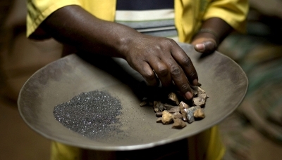 Ouvrier manipulant du coltan et des pierres de cassiterite dans une usine de transformation en RDC.