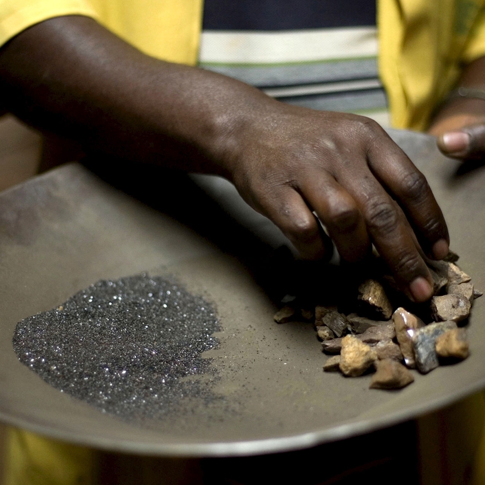 Ouvrier manipulant du coltan et des pierres de cassiterite dans une usine de transformation en RDC.