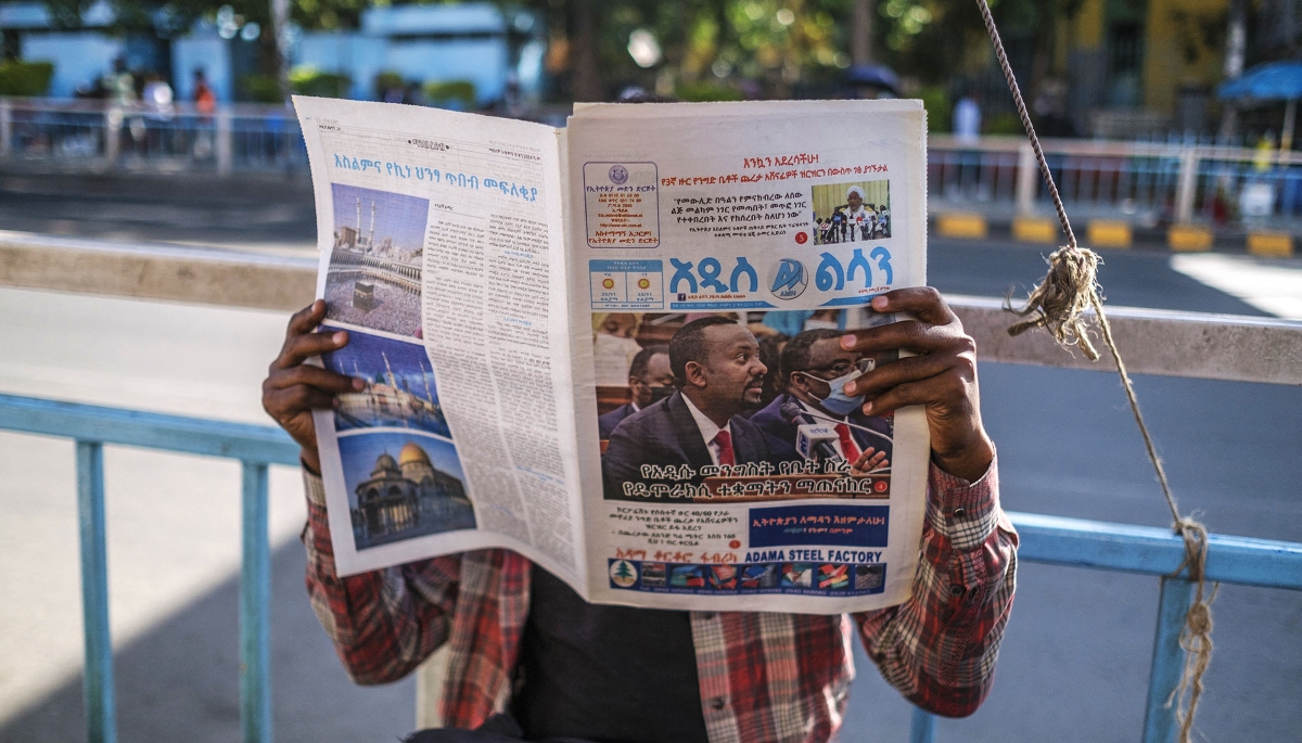 Un homme lisant le journal, dans le centre-ville d'Addis-Abeba, le 3 novembre 2021. En une, le premier ministre Abiy Ahmed.