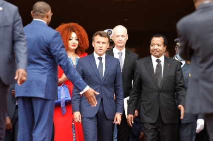 Le président français Emmanuel Macron et le président camerounais Paul Biya, ainsi que Chantal Biya aux côtés de l'ambassadeur de France au Cameroun Christophe Guilhou, sortent du palais présidentiel à Yaoundé, le 26 juillet 2022.