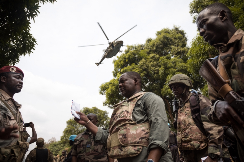 Le premier ministre alors en poste en République centrafricaine, Firmin Ngrebada (au centre), salue ses troupes, alors qu'un hélicoptère de soutien de fabrication russe les survole, sur la route entre Boali et Bangui, le 10 janvier 2021.